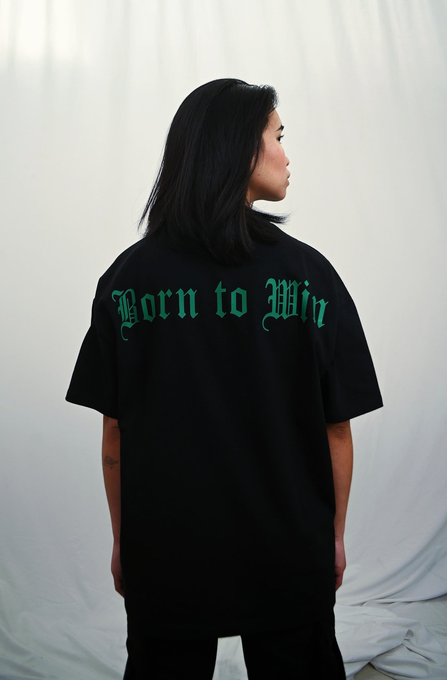 Female model wearing a Black oversize tshirt with green born to win design on the back