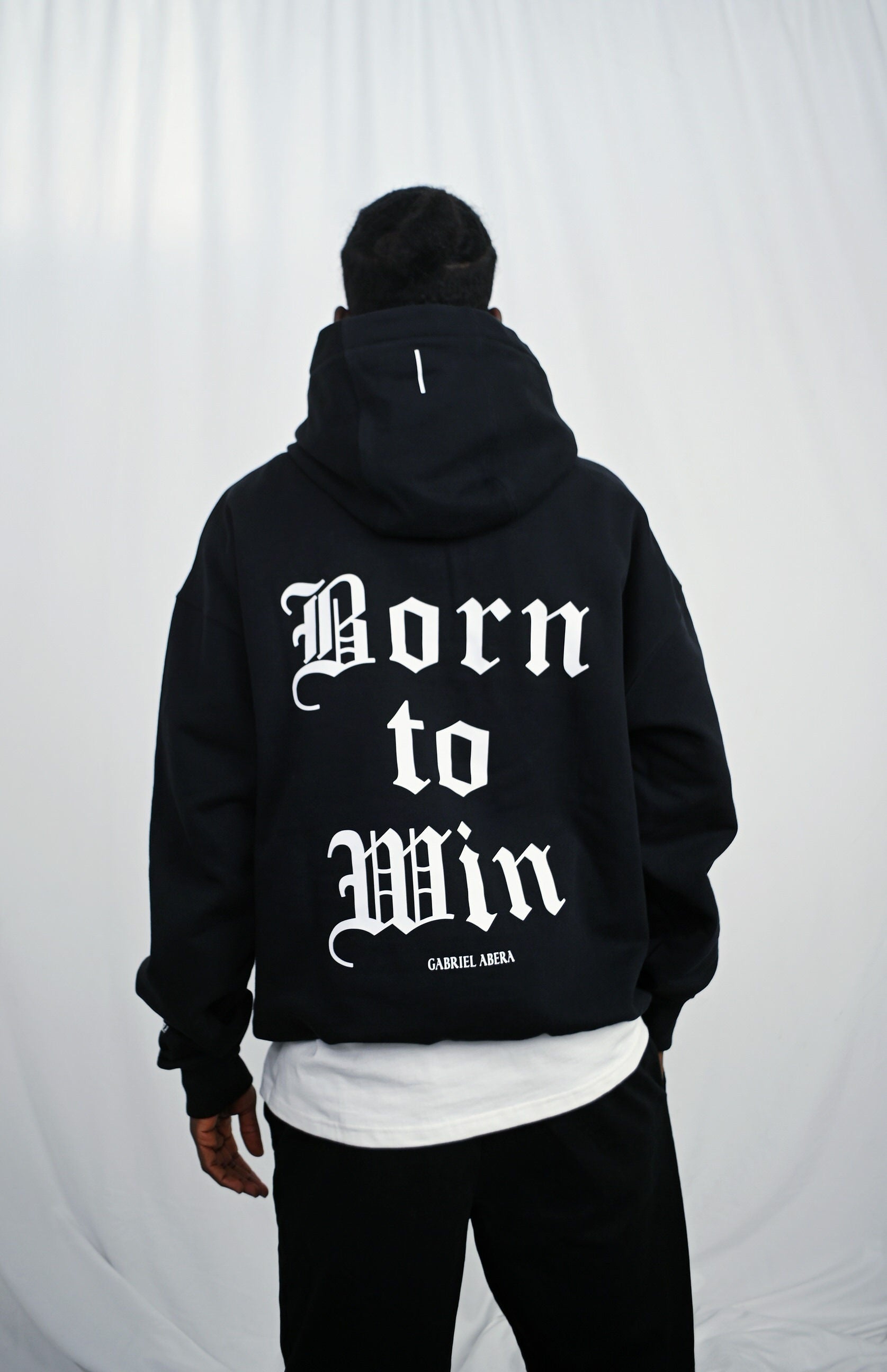 Male model wearing a Black oversize hoodie with white born to win design on the back