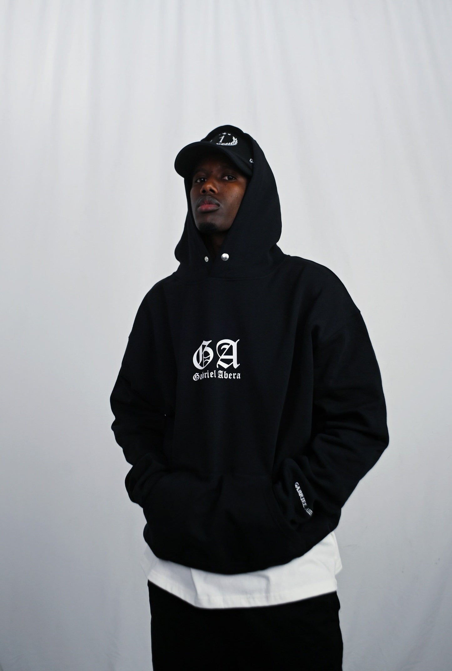 Male model wearing a Black oversize hoodie with white brand design on the front 