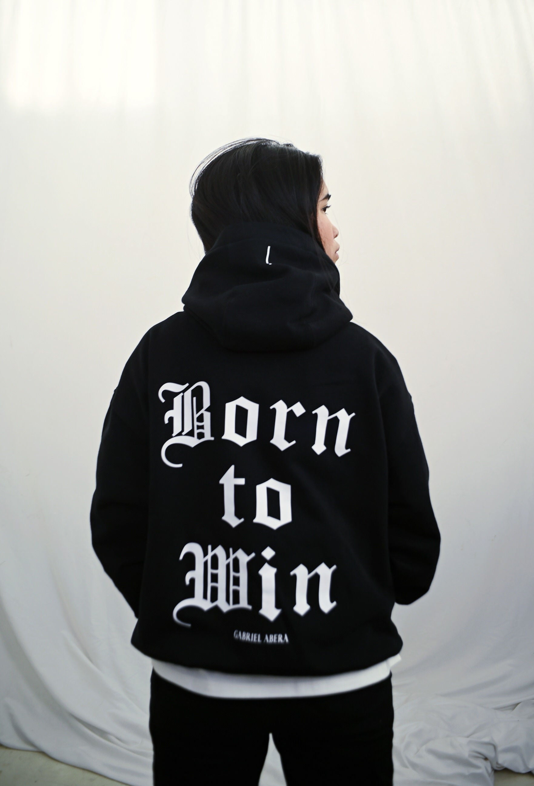 Female model wearing a Black oversize hoodie with white born to win design on the back
