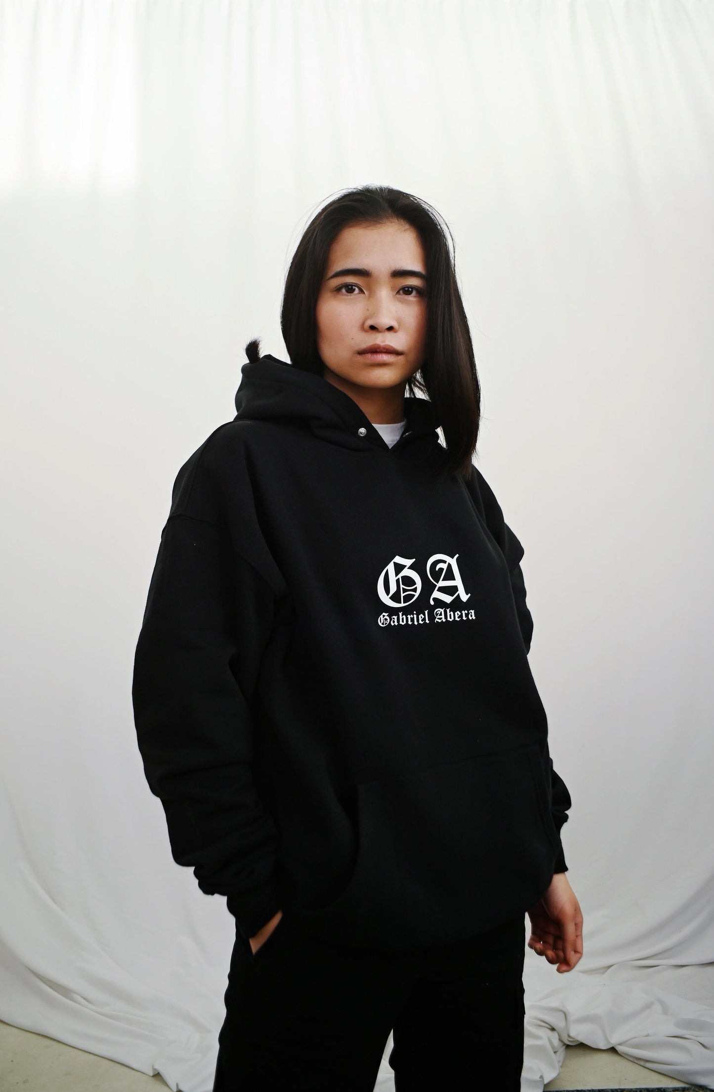 Female model wearing a Black oversize hoodie with white brand design on the front